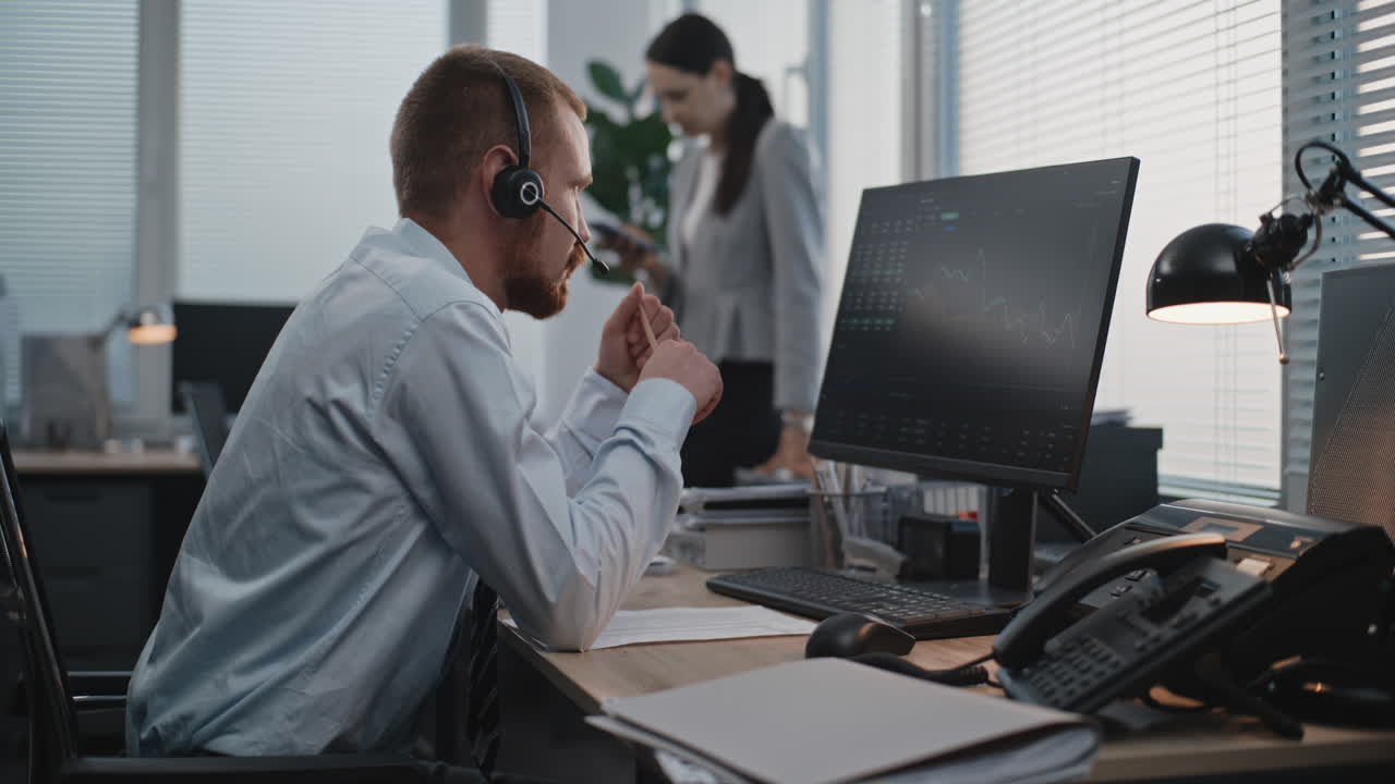 Businessperson in office using computer and headset