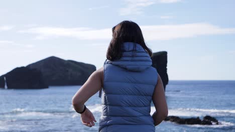 back of a tourist looking to the landmark volcanic rocks in mosteiros, azures