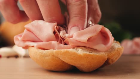 mortadella ham sandwich, traditional italian focaccia filled with thin pesto slices of mortadella, served by chef man in cafe restaurant. macro of traditional italian spanish tapas antipasti.