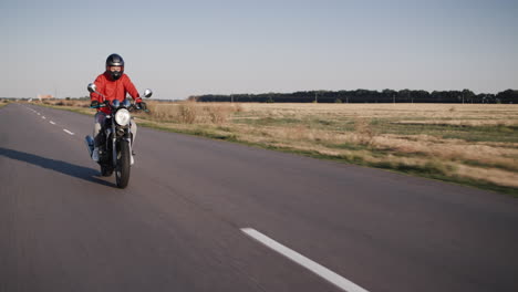 Motociclista-En-Una-Chaqueta-Roja-Paseos-En-Una-Carretera-Rural