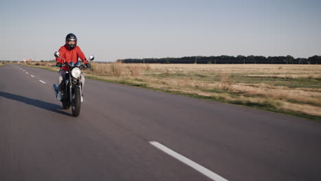 motorcyclist in a red jacket rides on a country road