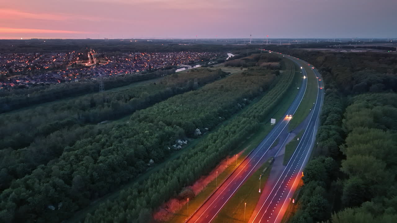 Calm drive through Dutch fields. Twilight illuminates a peaceful road winding through lush green fields in the Netherlands, surrounded by a small town