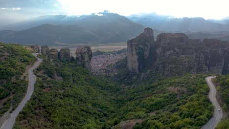meteora rocks and kalabaka city aerial panoramic shot, twisty mountain road in foreground, dolly shot