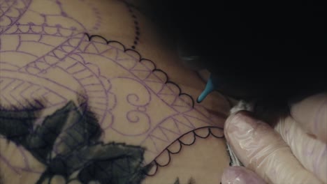artista del tatuaje aplicando tinta a mandala y diseño floral