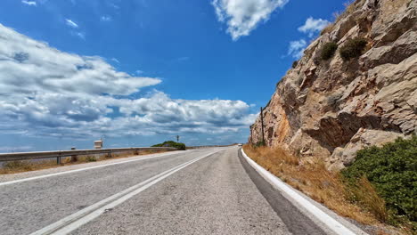 scenic drive along greek coastline or countryside with curving road along rocks