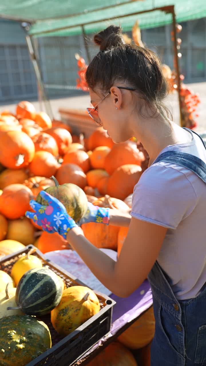 una mujer y una niña eligiendo calabazas en un mercado de otoño.