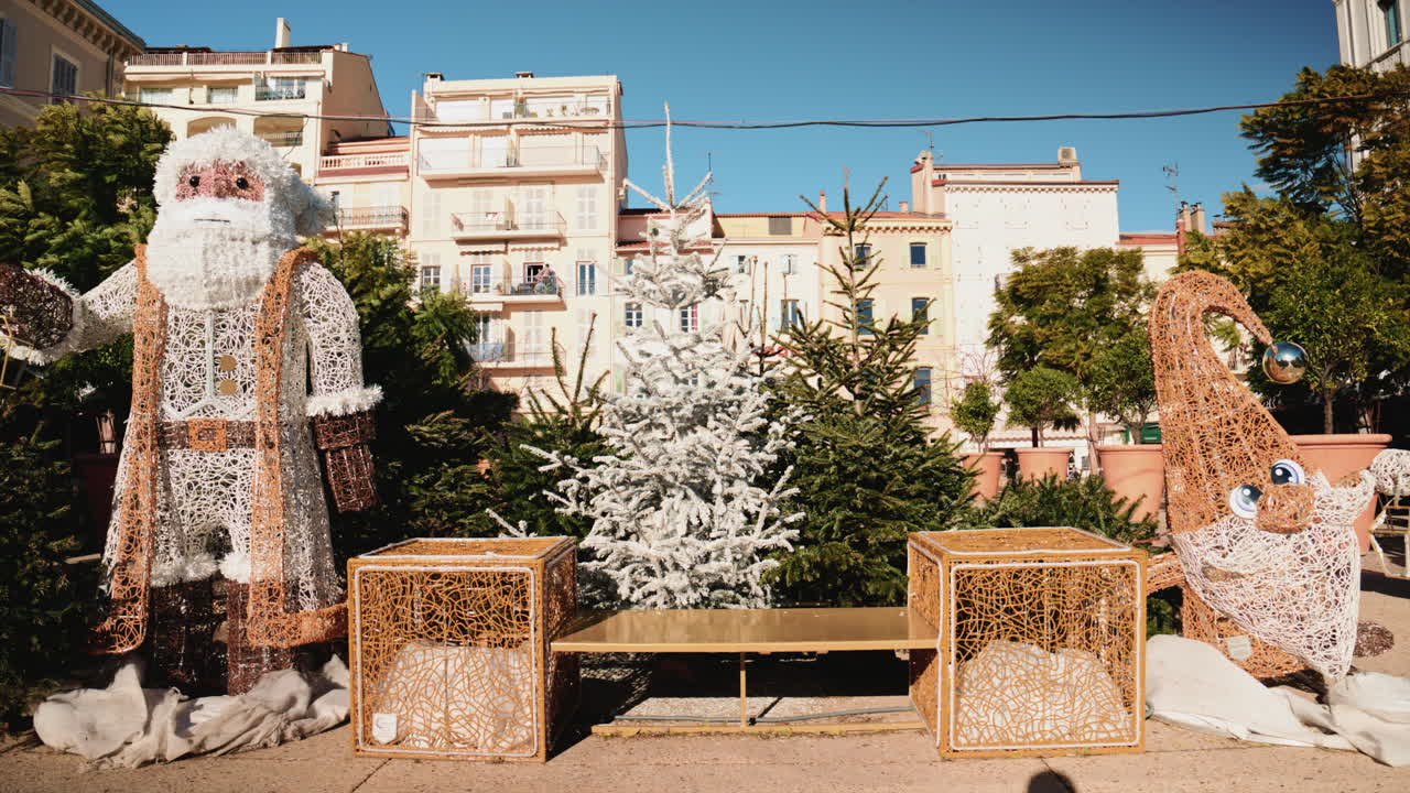 Weihnachtsinstallation im Freien mit großen Santa Claus- und Elfendekorationen, umgeben von Tannenbäumen