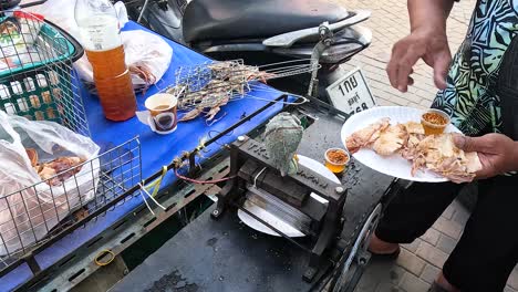 vendor prepares grilled squid with dipping sauce