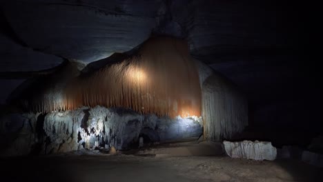 toma manual de una linterna que ilumina una enorme estructura de cueva naranja y blanca dentro de la famosa cueva lapa doce en el parque nacional chapada diamantina en bahia, noreste de brasil