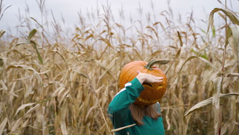 Niña-Con-Cabeza-De-Calabaza-Bailando-En-Los-Campos-De-Maíz