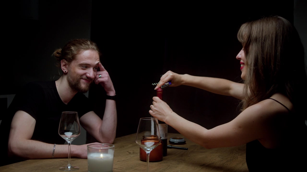 Joyous Woman On Date Night Opening Bottle Of Wine With Corkscrew. slow motion