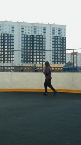 athlete jogging in outdoor sport arena surrounded by urban high-rise buildings, emphasizing movement, energy, and modern city lifestyle