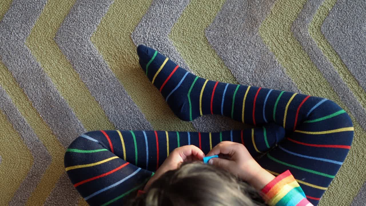 niño sentado en una alfombra de patrón zigzag con medias a rayas