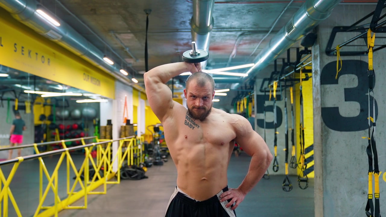 Uomo muscoloso in posa con un manubrio in una palestra moderna
