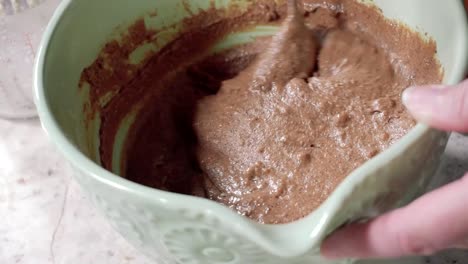primer plano revolviendo los arándanos y las chispas de chocolate en la masa de chocolate en un tazón grande