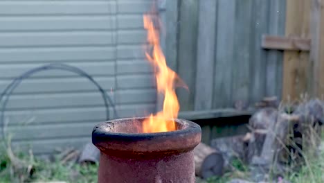 las llamas lamen la parte superior de una chimenea de terracota durante la noche