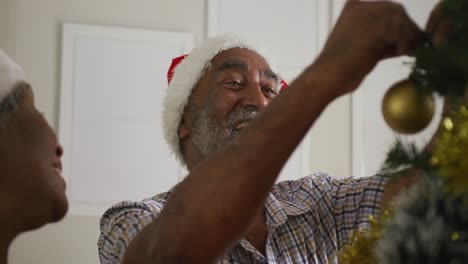 Animation-of-happy-african-american-senior-couple-decorating-christmas-tree-together