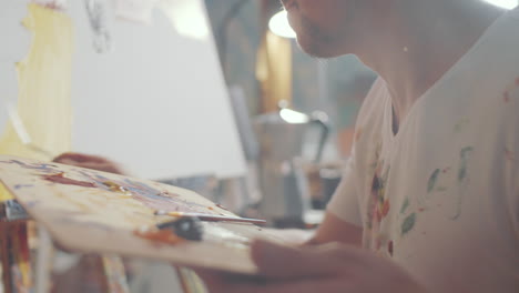 artist using palette knife for creating painting in studio