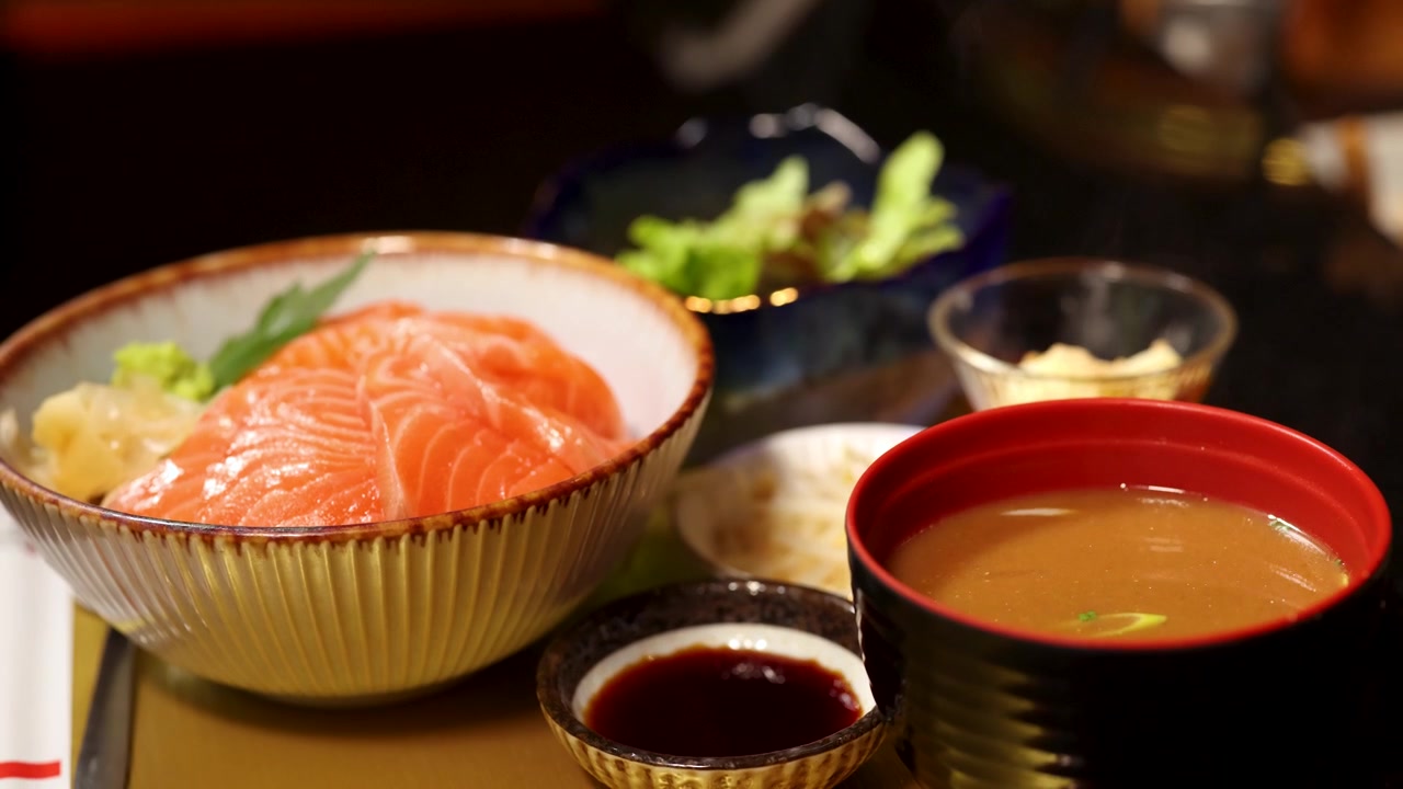 味噌汁とサラダが添えられた伝統的なサーモン刺身丼のクローズアップショット。