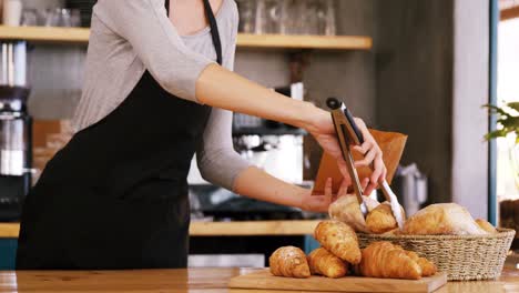 mid-section of waitress packing croissants in paper bag