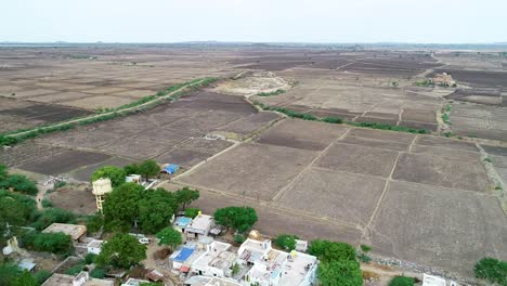 Luftschwenkansicht-Des-Kargen-Landwirtschaftlichen-Feldes-Am-Rande-Des-Dorfes-In-Indien