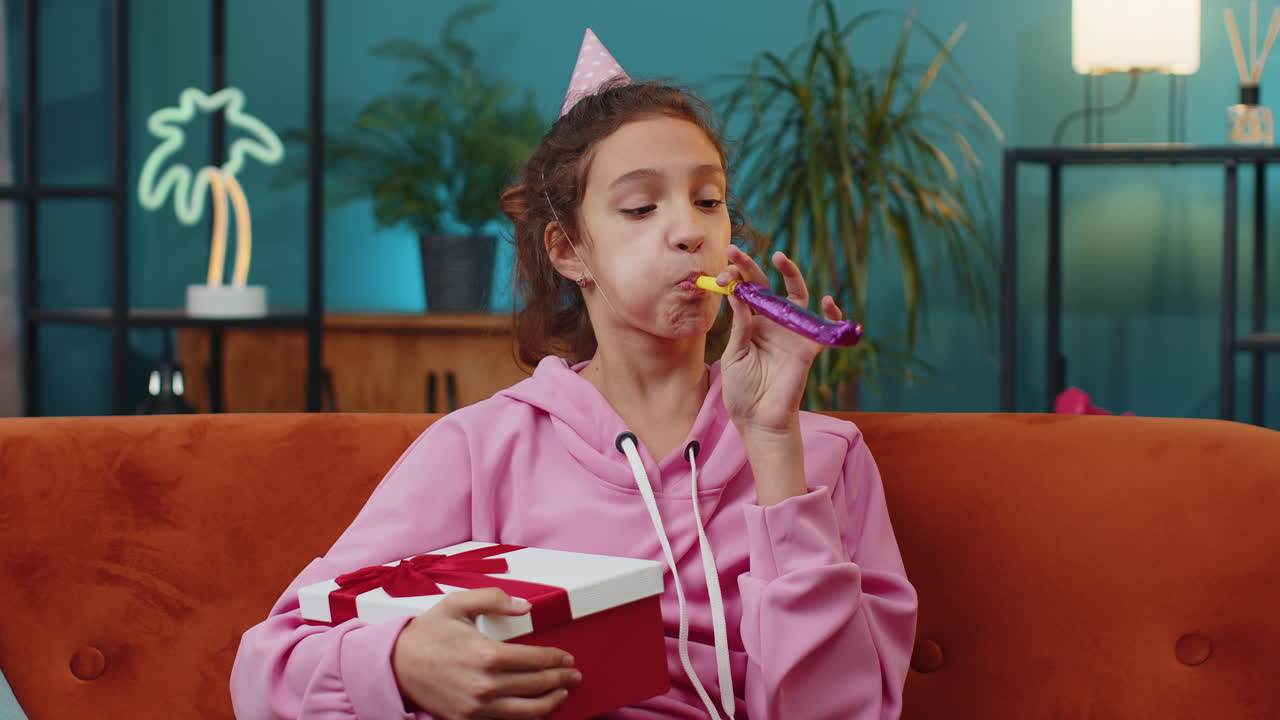 Felice e eccitata, fortunata ragazza che indossa un cappello di compleanno, un cono, un tubo da soffiare, che celebra il successo della festa, la vittoria della vittoria.