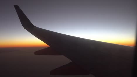 wing of airplane at sunrise blocks out the sunlight. view from the window of the plane. aircraft flight on sunset. traveling by air.