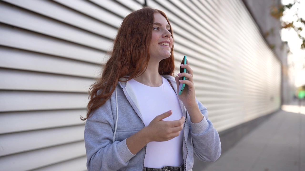 Una giovane donna con uno smartphone in un contesto urbano sembra profondamente assorta nell'ambiente circostante.