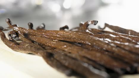 dolly shot along pile of vanilla pods on table in slow motion, selective focus