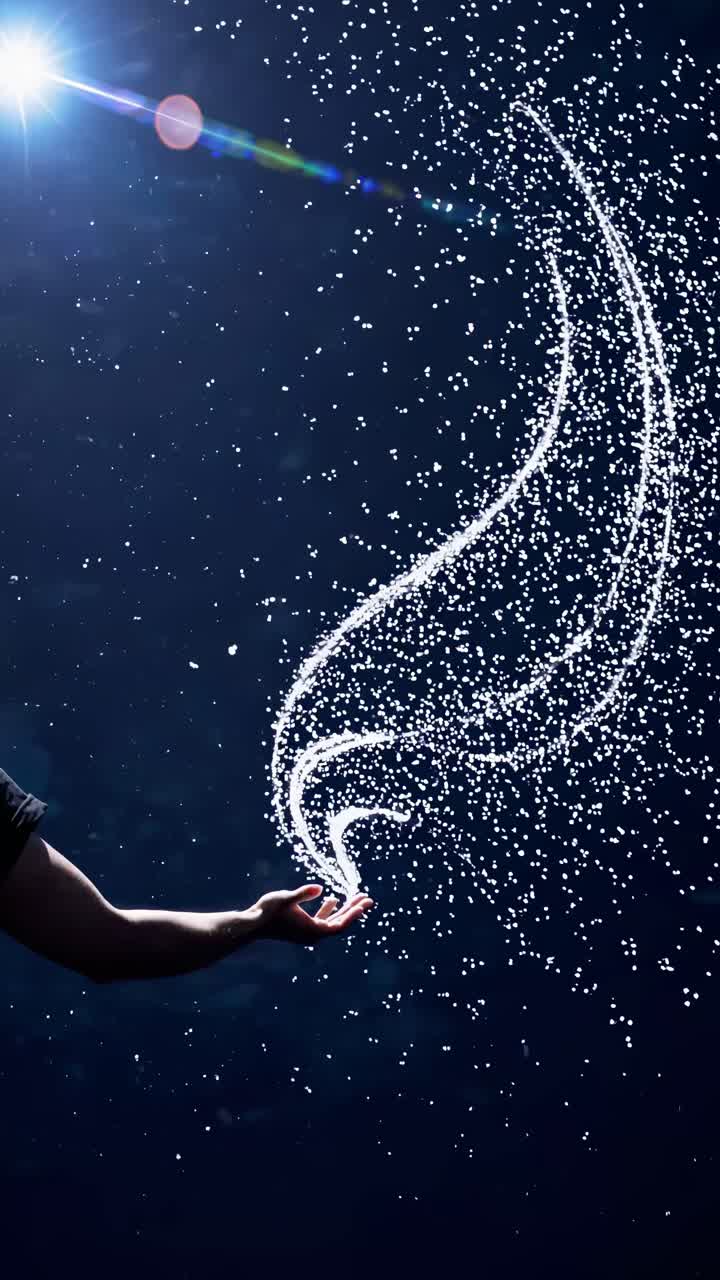 A mesmerizing video concept with a low-angle shot of a hand releasing sparkling particles