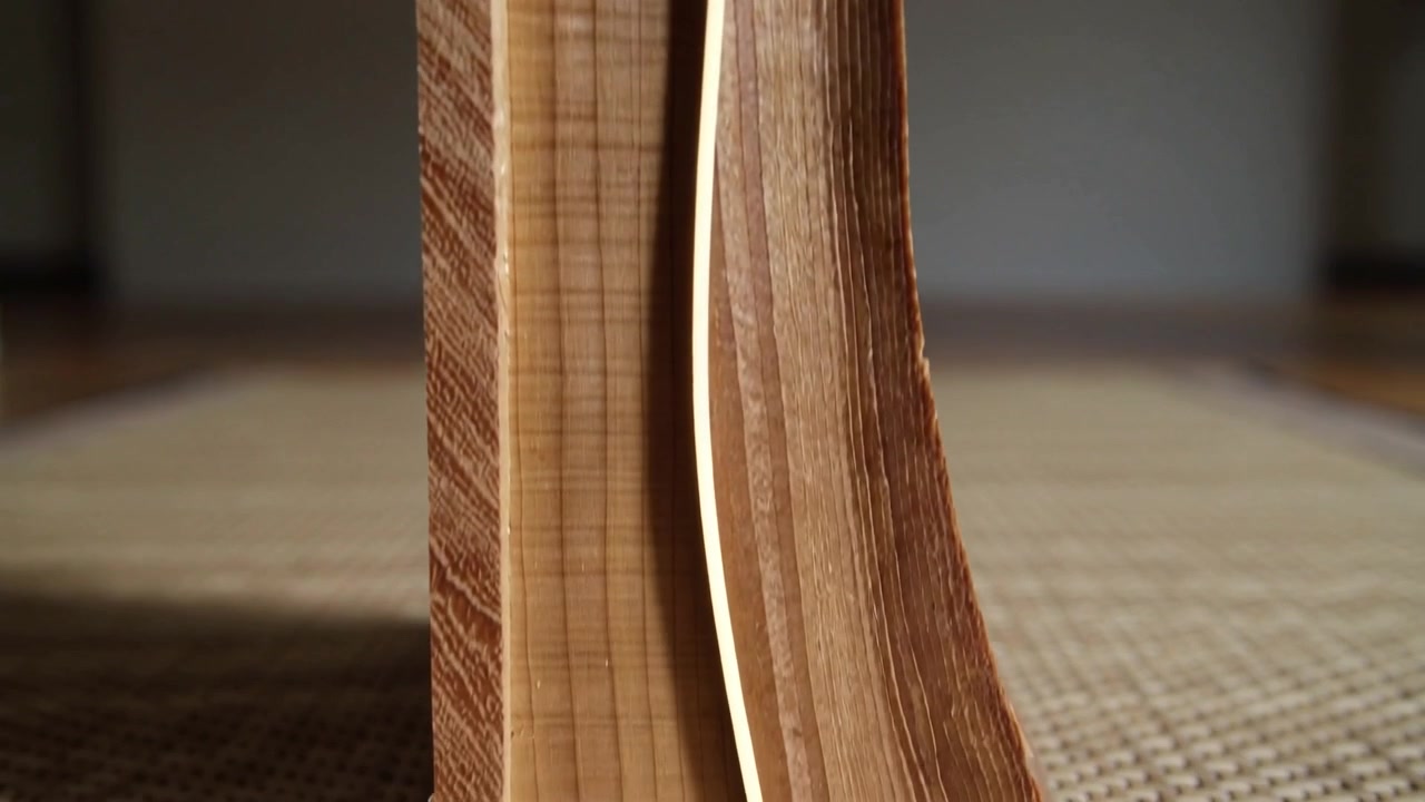 Lamella laminata che si piega rilasciando la tensione da un blocco dritto su una stuoia di paglia, cucitura luminosa che si allarga