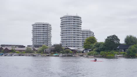 person in canoe like boat paddle in city river canal, copenhagen, denmark