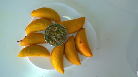 delicious empanadas in a plate with guacamole salsa dip in a small bowl - overhead shot