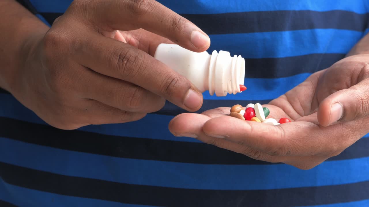 Person pouring pills out of a bottle into their hand