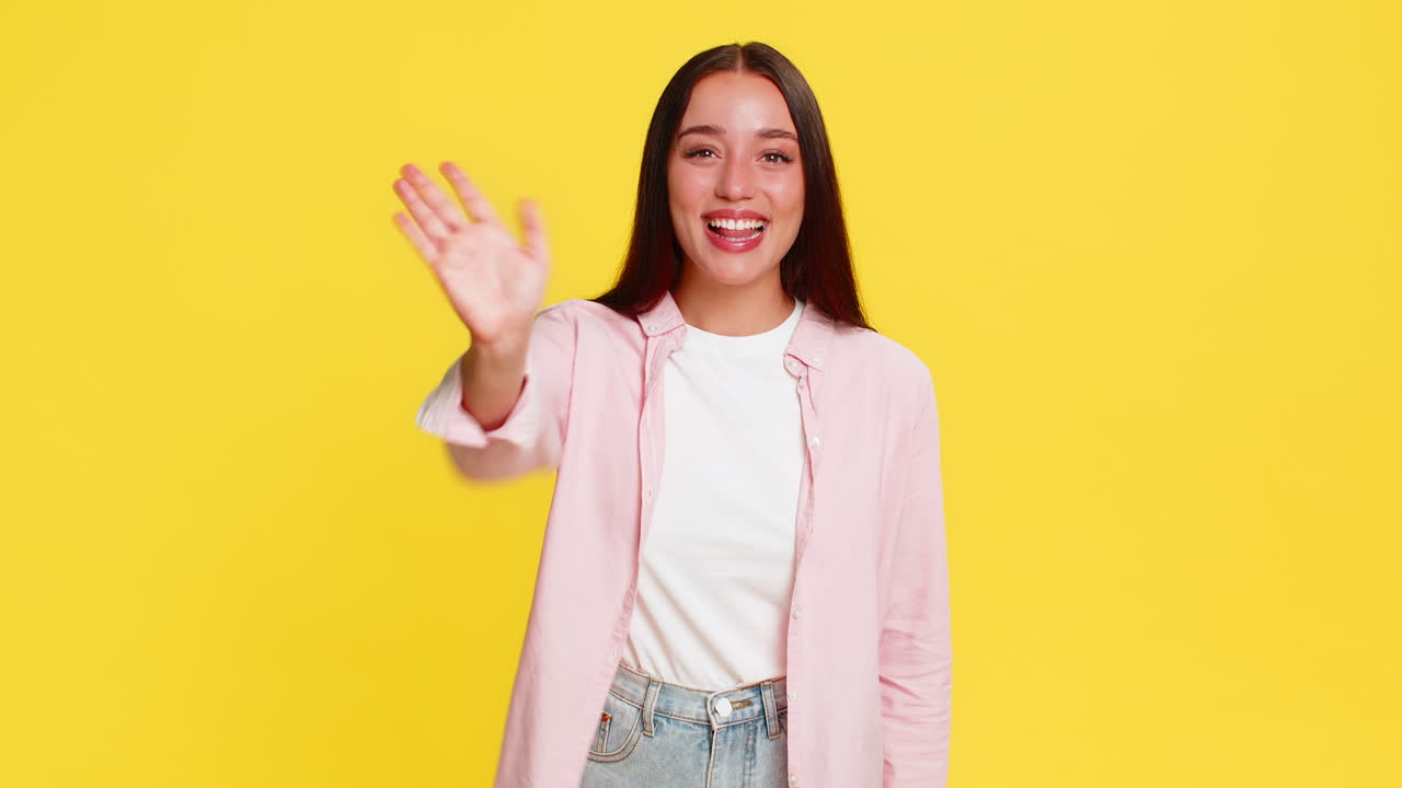 Young woman smiling waving hand friendly cheerful hello gesture positive happy emotional greeting