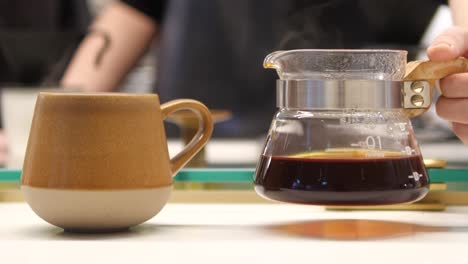 young man hand keep down glass jar of coffee in cafe on table