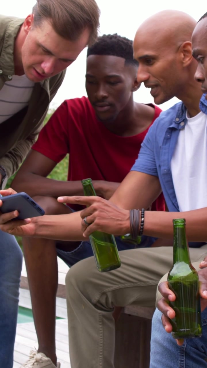 Vertical video: Starting man showing smartphone to friends by pool to share, with green bottles