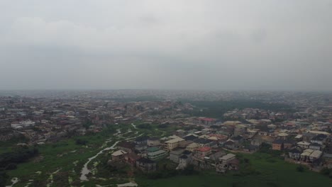 Vista-Aérea-Del-Barrio-En-Lagos-Nigeria-En-Un-Día-Brumoso-Con-Drones-Cayendo-Para-Revelar-Un-Verde