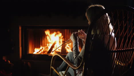 woman doing needlework sitting by the fireplace winter leisure