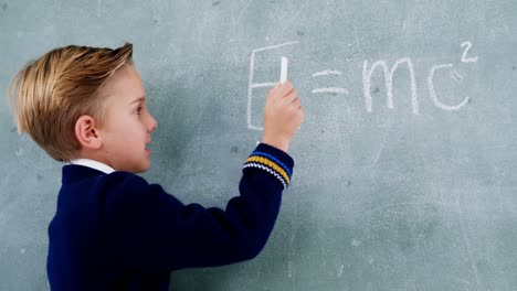 schoolboy doing maths on chalkboard