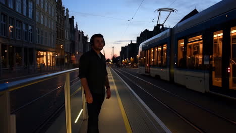 man on a tram platform at dusk
