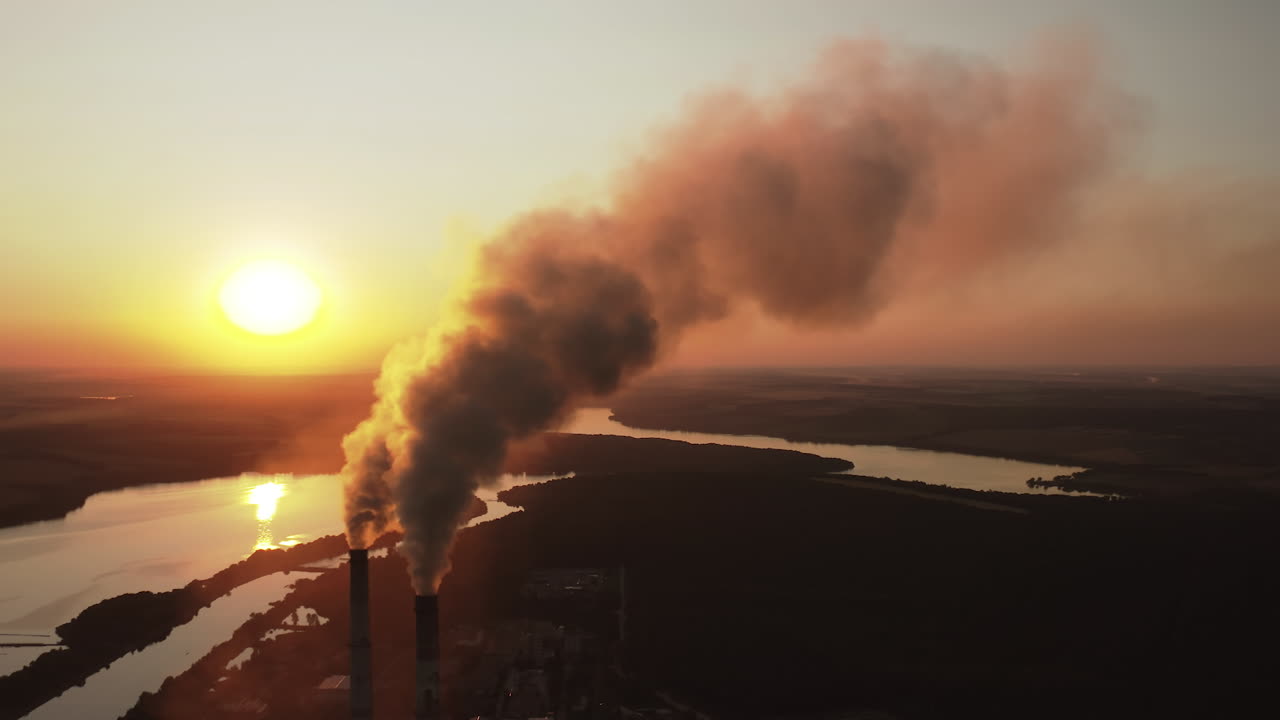 Large plant with smoking pipes. Dark smoke comes out in clouds from chimney of factory plant