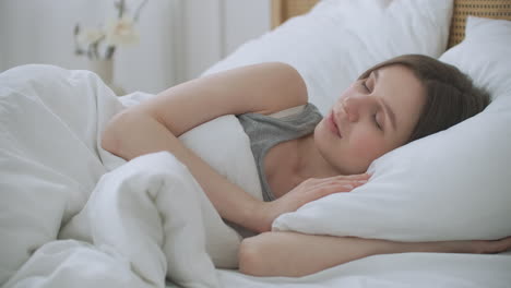 Smiling-Woman-Waking-Up.-Teen-hispanic-woman-wakes-up-at-home.-Young-girl-stretching-after-awake-starting-a-new-day-with-energy-and-vitality-on-bed-near-window-in-bedroom-at-morning-back-view.