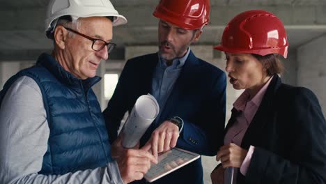 Static-and-close-up-footage-of-group-of--caucasian-engineers-and-investors-standing-and-discussing-on-construction-site.-S