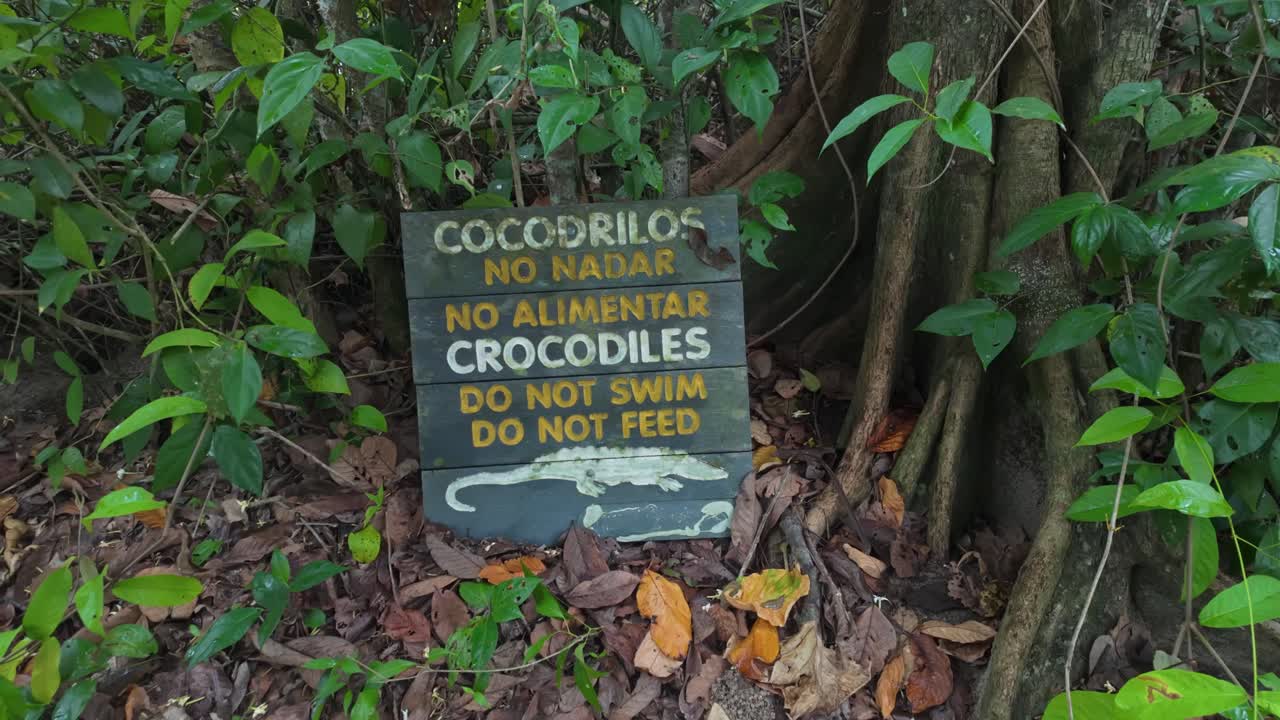 Warning sign about swimming and feeding actions with crocodiles in Cahuita National Park, Costa Rica