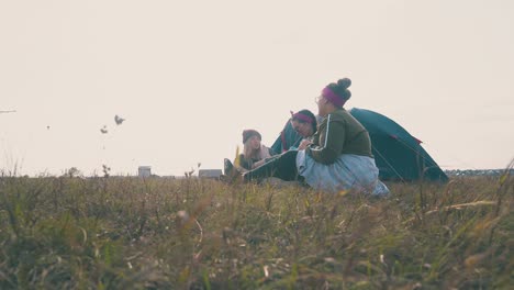 pretty friends spend time at tent against sky in evening