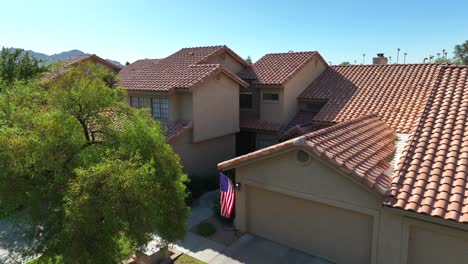 American-flag-waving-on-house-with-stucco-design-and-shingle-roof