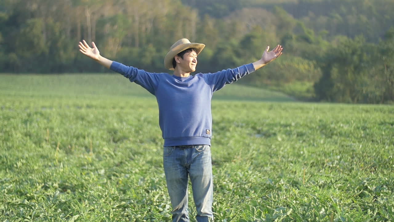 Farmer Standing With Arms Outstretched At Melon Field