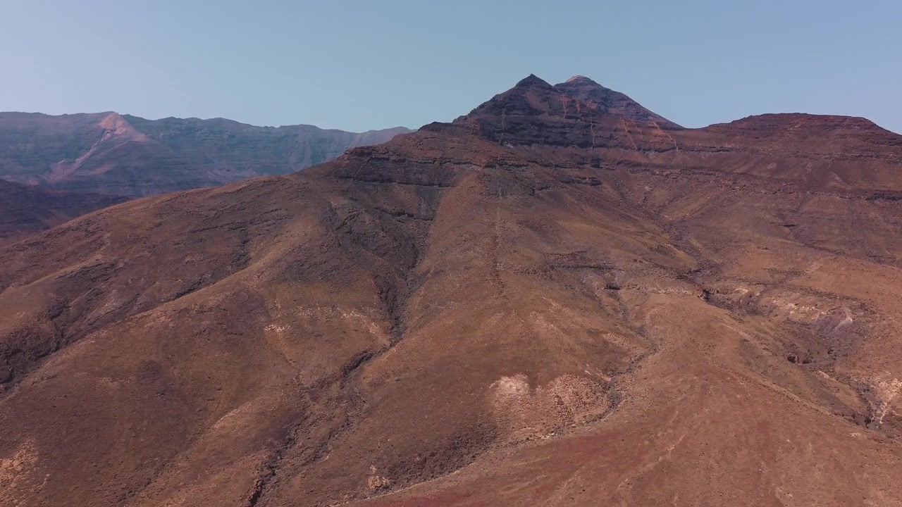 Vista aerea di un paesaggio montano arido sotto un cielo azzurro e limpido