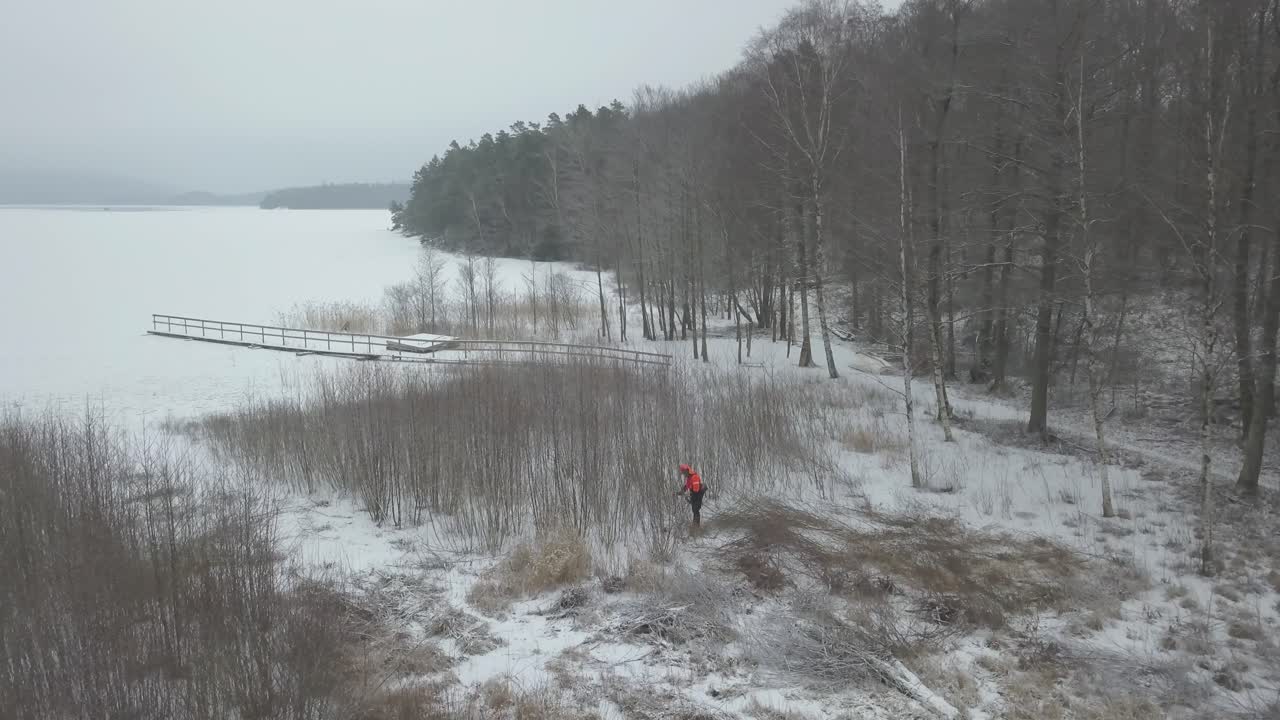 un trabajador forestal junto a un lago de invierno